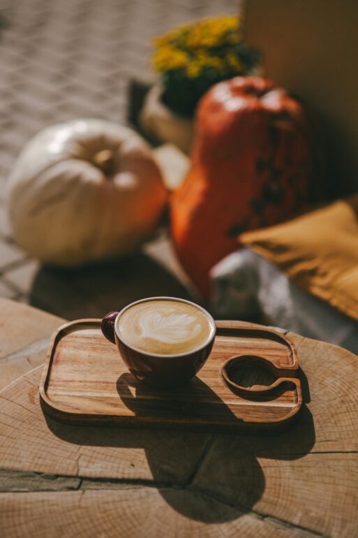 Warm and inviting autumn scene with a latte and pumpkins on a rustic table.