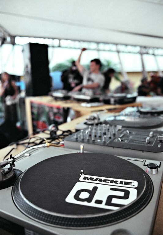 Dynamic outdoor music event at Miami Beach featuring a DJ with turntables and a vibrant crowd.